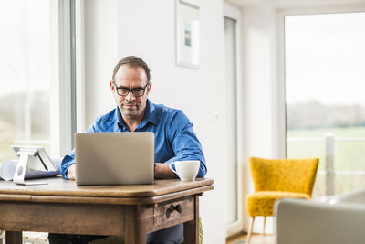 Businessman at home with laptop at wooden table