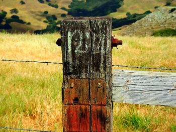 Close-up of wooden post on field against sky