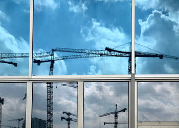 Low angle view of cranes at construction site against sky