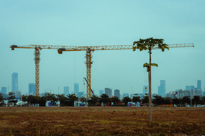 Cranes at construction site against clear blue sky