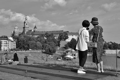 Rear view of people looking at city against sky