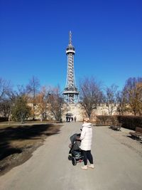 Woman with baby stroller using mobile phone in city
