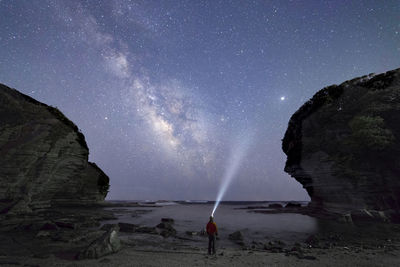 Man standing on field against sky at night