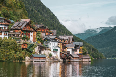 Houses by lake and buildings against sky