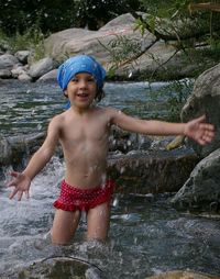 Portrait of shirtless boy standing in river