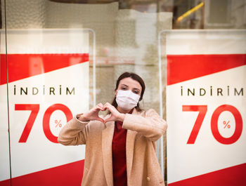 Portrait of woman gesturing while standing against information sign