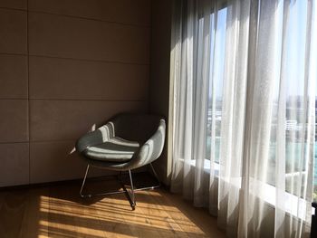 Empty chair by window curtain at home