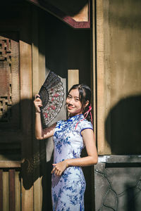 Portrait of young woman standing against wall