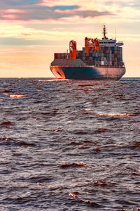 Ship sailing on sea against sky during sunset