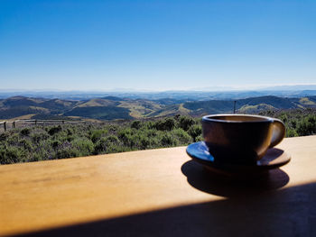 Coffee cup on table against mountains