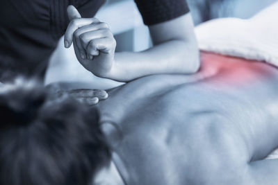 Cropped image of woman massaging customer back at spa