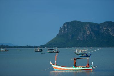 Fishing boats in sea against clear sky