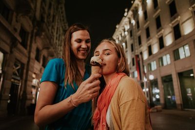 Portrait of young women with ice cream cone in city