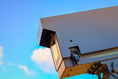 Low angle view of security camera against blue sky