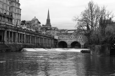 Arch bridge over river against buildings