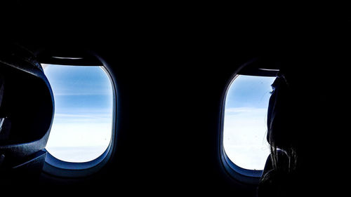 Woman looking through airplane window while traveling