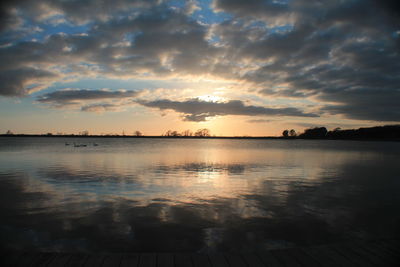 Scenic view of sea against cloudy sky at sunset