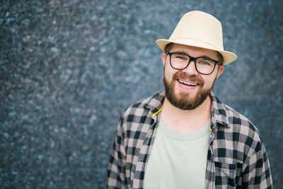 Happy man wearing hat standing against wall