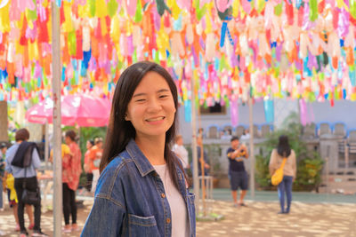 Smiling woman standing against multi colored paper lanterns