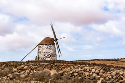 Traditional windmill on landscape against sky