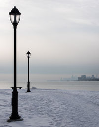 Street light by sea against sky