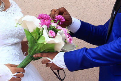 Midsection of couple holding bouquet