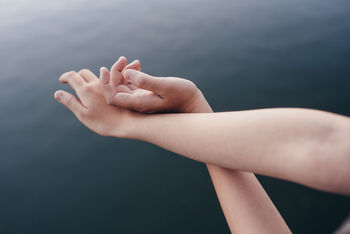 Cropped hands of person against sea