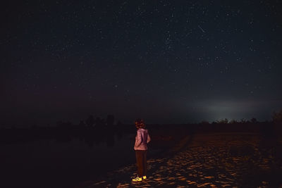 Rear view of man standing on field at night