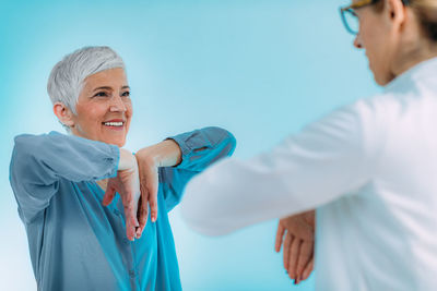 Doctor doing medical exam with senior woman, checking for carpal tunnel syndrome.