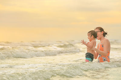 People on beach against sky during sunset