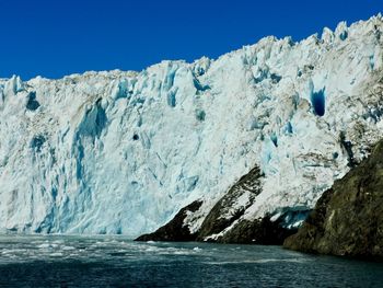 Scenic view of glacier and sea against clear sky