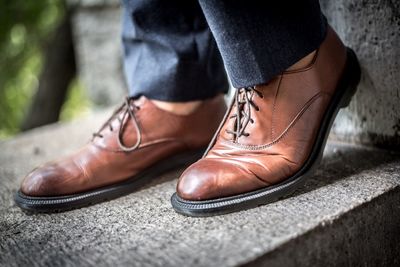 Low section of man wearing brown shoes on retaining wall