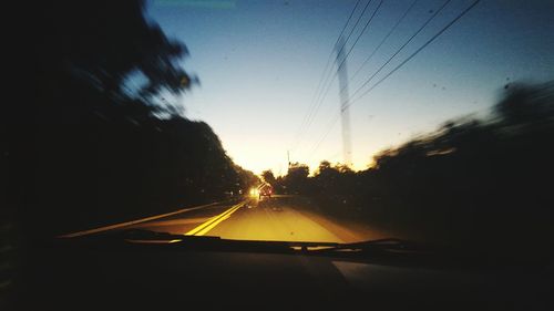 Road seen through car windshield during sunset