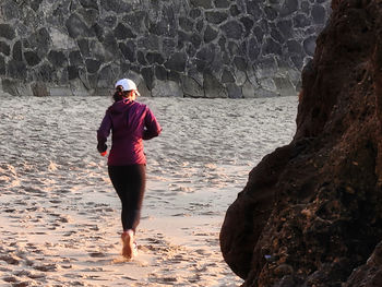 Rear view of man standing on rock at beach