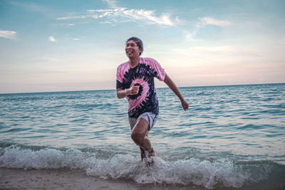 Full length of man jumping on beach against sky