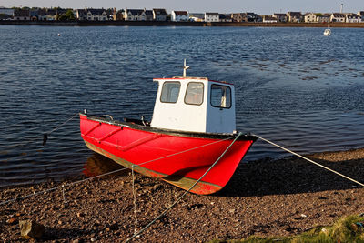 Red boat moored on sea against sky