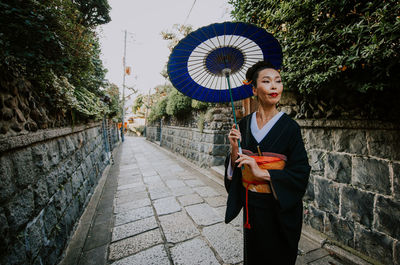 Woman standing on footpath amidst buildings