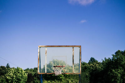 Basketball court against trees and blue sky