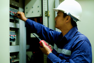 Midsection of man inspecting fuse box
