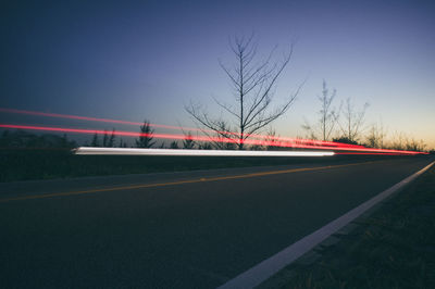 Light trails on road against clear sky at night