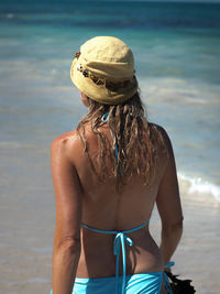 Rear view of woman in bikini standing at beach