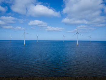 Wind turbines in sea against sky