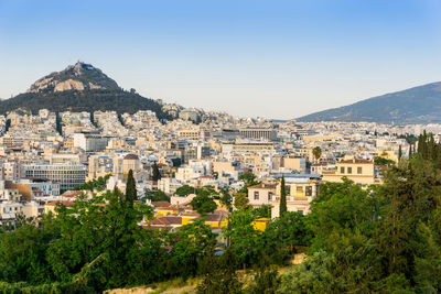 High angle view of cityscape by mountain against clear sky