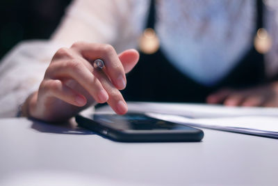 Midsection of man using mobile phone on table