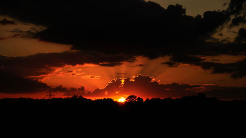 Silhouette landscape against dramatic sky during sunset