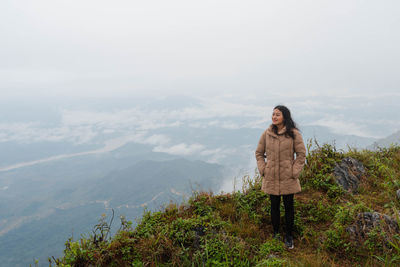 Asian woman in winter coat on mountain peak at pha tang view point 103 with heavy fog sky. 