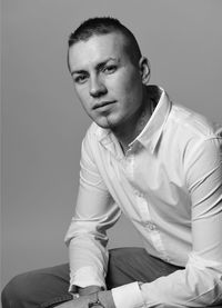 Portrait of young man sitting against wall