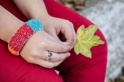 High angle view of woman holding red leaf