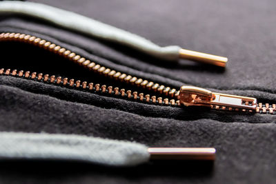 Copper colored fashion zipper in close-up macro view showing black sweatshirt with opened zipper