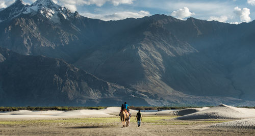 Rear view of people walking against mountain